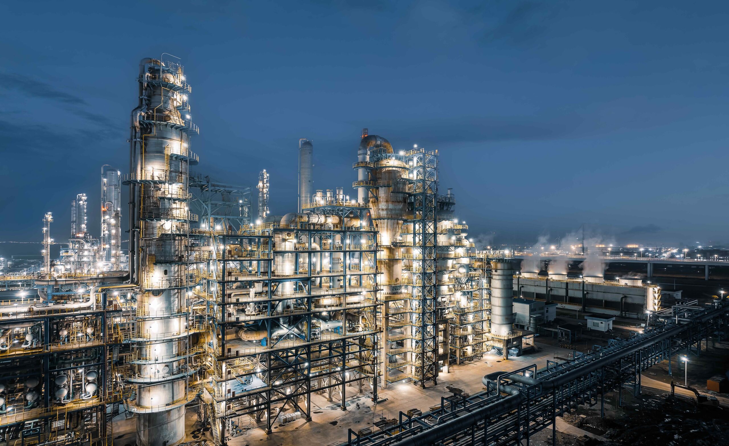 Industrial chemical plant equipment and pipelines at night view.